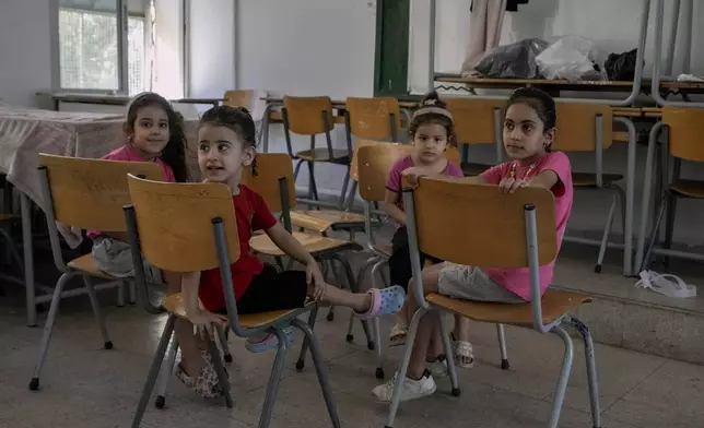 Displaced children sit in a classroom in Beirut, after fleeing the Israeli airstrikes in the south with their families, Thursday, Sept. 26, 2024. (AP Photo/Bilal Hussein)