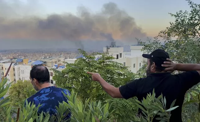 Lebanese citizens watch smoke rise from Israeli airstrikes in the southern suburbs of Beirut, Lebanon, Saturday, Sept. 28, 2024. (AP Photo/Hussein Malla)