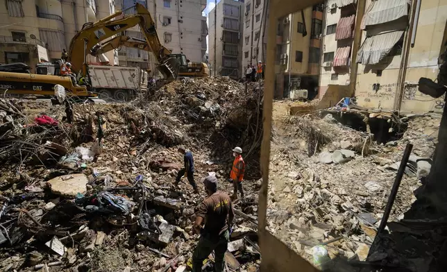 Emergency workers use excavators to clear the rubble at the site of Friday's Israeli strike in Beirut's southern suburbs, Lebanon, Monday, Sept. 23, 2024. (AP Photo/Hassan Ammar)