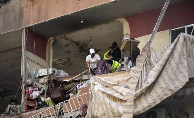 Residents and rescuers check a building that was hit by an Israeli airstrike in Beirut's southern suburbs, Tuesday, Sept. 24, 2024. (AP Photo/Hassan Ammar)