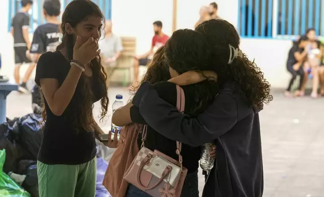 Displaced youth hug as they take shelter at a school in Beirut, after fleeing the Israeli airstrikes in the south with their families, Thursday, Sept. 26, 2024. (AP Photo/Bilal Hussein)