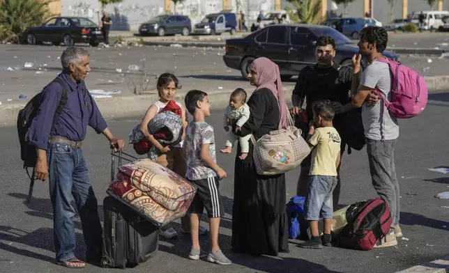 Families carry their belongings in Beirut's Martyrs' square after fleeing the Israeli airstrikes in the southern suburbs of Dahiyeh, Saturday, Sept. 28, 2024. (AP Photo/Bilal Hussein)