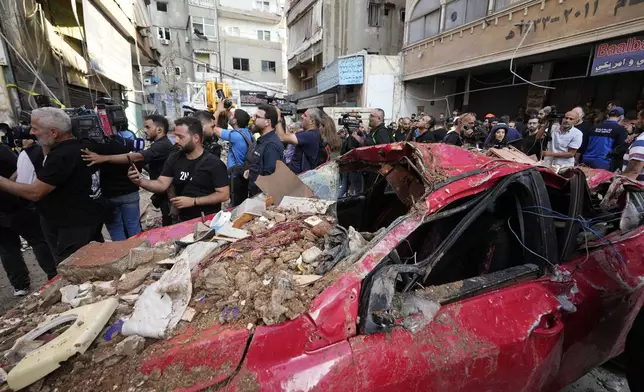 Journalists gather at the scene of a building that was hit by an Israeli airstrike in Beirut's southern suburbs, Tuesday, Sept. 24, 2024. (AP Photo/Hassan Ammar)