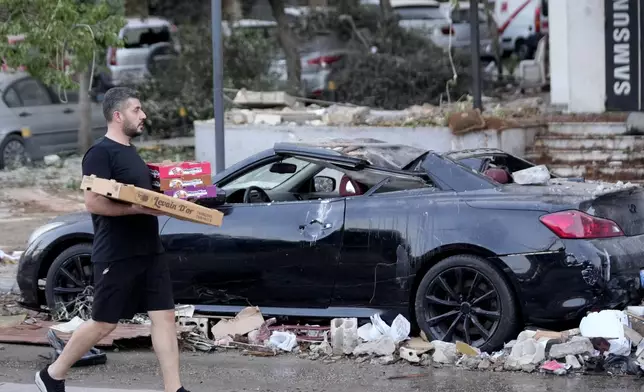 A man passes by a damaged car where an Israeli airstrike hit a nearby building in Beirut, Lebanon, early Monday, Sept. 30, 2024. (AP Photo/Hussein Malla)