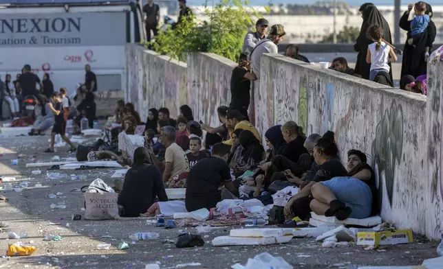 Families sit on the ground in Martyrs' square after fleeing the Israeli airstrikes in Beirut's southern suburbs, Saturday, Sept. 28, 2024. (AP Photo/Bilal Hussein)