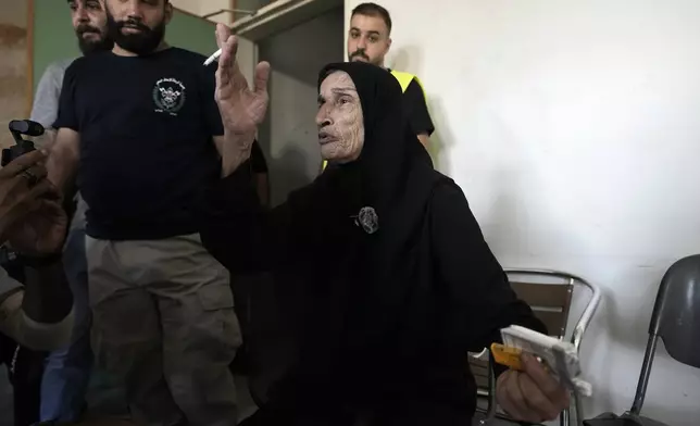 A woman, who fled the Israeli airstrikes in the south, reacts as she arrives at a school turned into a shelter in Beirut, Monday, Sept. 23, 2024. (AP Photo/Bilal Hussein)