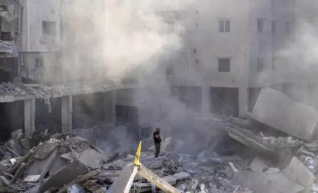 A man stands on the rubble of buildings near the site of the assassination of Hezbollah leader Hassan Nasrallah in Beirut's southern suburbs, Sunday, Sept. 29, 2024. (AP Photo/Hassan Ammar)