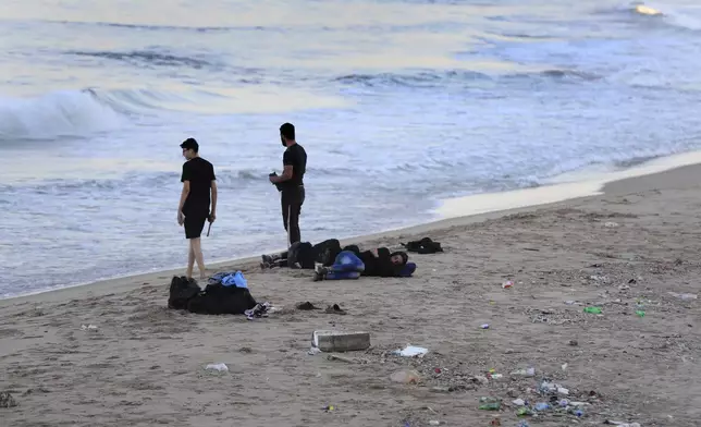 Lebanese men who fled on the southern villages amid ongoing Israeli airstrikes Monday, sleep on a public beach in the southern port city of Sidon, Lebanon, Tuesday, Sept. 24, 2024. (AP Photo/Mohammed Zaatari)