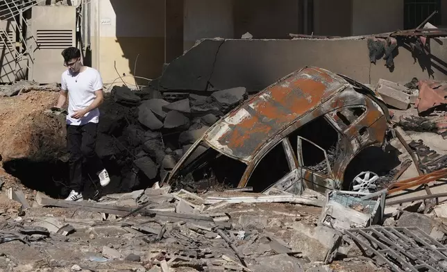 A man walks on rubble at the site of an Israeli airstrike in Beirut's southern suburbs, Sunday, Sept. 29, 2024. (AP Photo/Hassan Ammar)