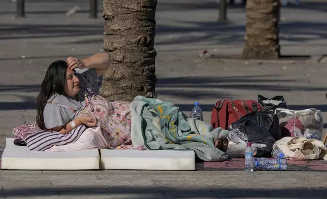 A woman sleeps on Beirut's corniche after fleeing the Israeli airstrikes in the southern suburbs of Dahiyeh, Sunday, Sept. 29, 2024. (AP Photo/Bilal Hussein)