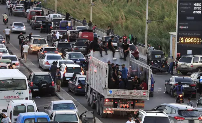 Lebanese citizens who fled on the southern villages amid ongoing Israeli airstrikes Monday, sit on their cars at a highway that links to Beirut city, in the southern port city of Sidon, Lebanon, Tuesday, Sept. 24, 2024. (AP Photo/Mohammed Zaatari)