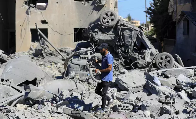 A man carries a damaged bicycle at the site of an Israeli airstrike in Saksakieh, south Lebanon, Thursday, Sept. 26, 2024. (AP Photo/Mohammed Zaatari)