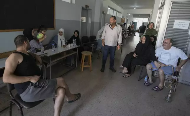 Displaced people gather in the hallway of a school in Beirut, after fleeing the Israeli airstrikes in the south, Thursday, Sept. 26, 2024. (AP Photo/Bilal Hussein)