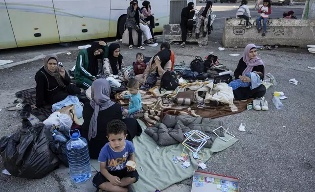 Families sit on the ground in Martyrs' square after fleeing the Israeli airstrikes in Beirut's southern suburbs, Saturday, Sept. 28, 2024. (AP Photo/Bilal Hussein)