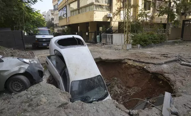 A car sits in a crater in Beirut's southern suburbs, Saturday, Sept. 28, 2024. (AP Photo/Hussein Malla)