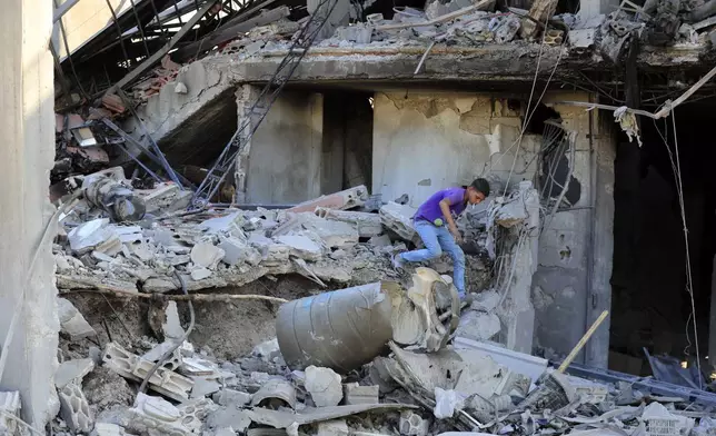 A boy checks the damage to a building hit in an Israeli airstrike in the southern village of Akbieh, Lebanon, Tuesday, Sept. 24, 2024. (AP Photo/Mohammed Zaatari)