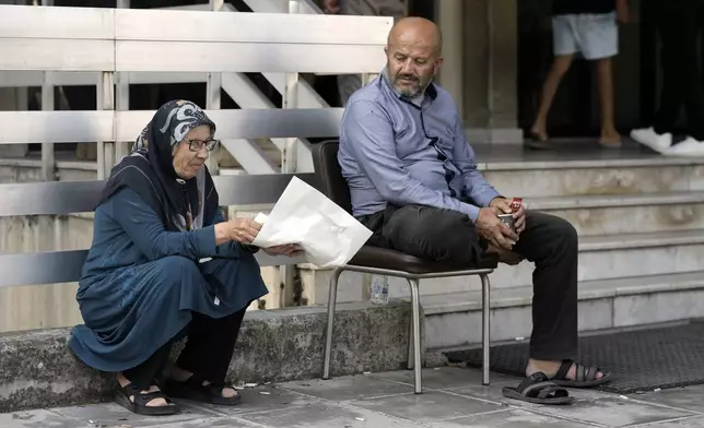 A couple sit outside a school turned into a shelter in Beirut, after fleeing the Israeli airstrikes in the southern village of Houla, Tuesday, Sept. 24, 2024. (AP Photo/Bilal Hussein)