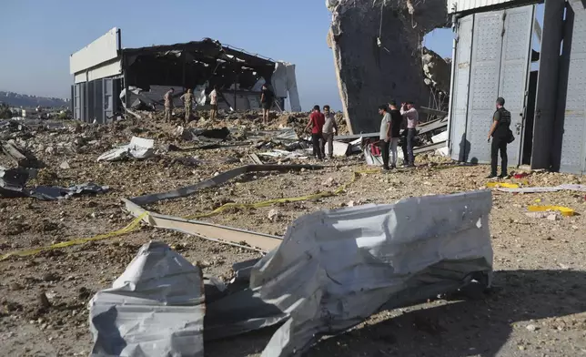 People gather near the site of an Israeli airstrike that hit a hangar in the southern town of Jiyeh, Lebanon, Wednesday, Sept. 25, 2024. (AP Photo/Mohammed Zaatari)