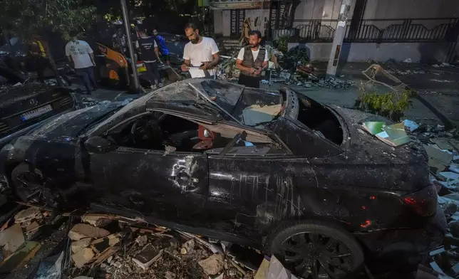 People inspect a damaged car near a building that was hit in an Israeli airstrike, in Beirut, Lebanon, early Monday, Sept. 30, 2024. (AP Photo/Bilal Hussein)