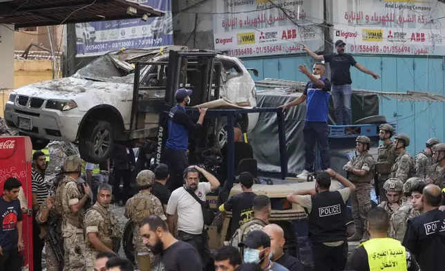 A forklift removes a damaged car as Lebanese army and emergency workers gather at the scene of an Israeli airstrike in Beirut's southern suburbs, Tuesday, Sept. 24, 2024. (AP Photo/Hassan Ammar)