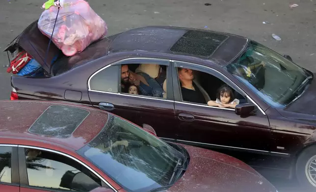 Lebanese citizens who fled the southern villages amid ongoing Israeli airstrikes Monday, sit in their cars at a highway that links to Beirut city, in the southern port city of Sidon, Lebanon, Tuesday, Sept. 24, 2024. (AP Photo/Mohammed Zaatari)