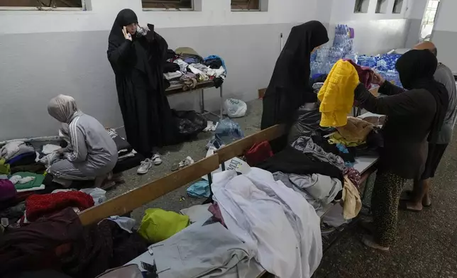 Volunteers distribute clothes to displaced women at a school in Beirut, Thursday, Sept. 26, 2024. (AP Photo/Bilal Hussein)