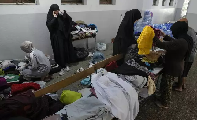 Volunteers distribute clothes to displayed women at a school in Beirut, Thursday, Sept. 26, 2024. (AP Photo/Bilal Hussein)