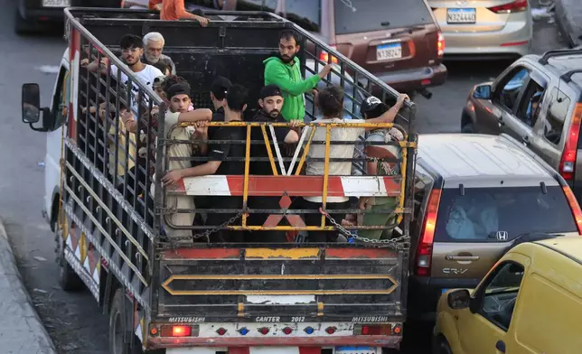 Lebanese citizens who fled on he southern villages amid ongoing Israeli airstrikes Monday, stand on a pickup at a highway that links to Beirut city, in the southern port city of Sidon, Lebanon, Tuesday, Sept. 24, 2024. (AP Photo/Mohammed Zaatari)