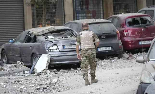 A Lebanese soldier passes next to damaged cars where an Israeli airstrike hit a building in Beirut early Monday, Sept. 30, 2024. (AP Photo/Hussein Malla)