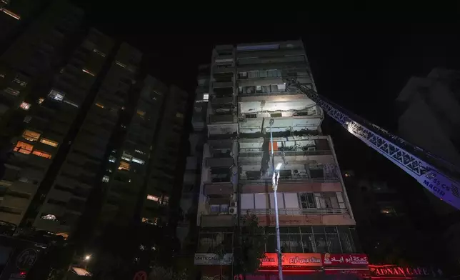 A fire engine ladder extends up a building that was hit in an apparent Israeli airstrike, in central Beirut, Lebanon, early Monday, Sept. 30, 2024. (AP Photo/Bilal Hussein)