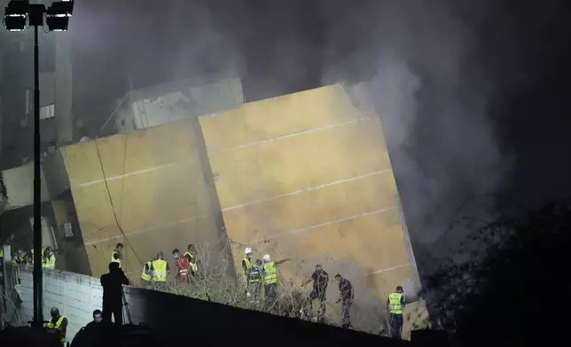 Rescuers gather as smoke rises from a collapsed building at the site of an Israeli airstrike in Beirut's southern suburbs, Friday, Sept. 27, 2024. (AP Photo/Hassan Ammar)