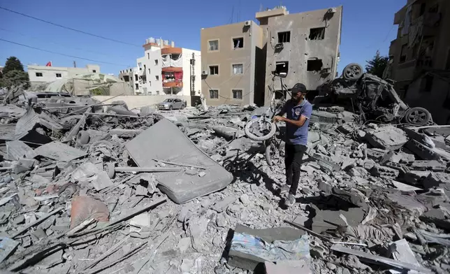 A man carries a damaged bicycle at the site of an Israeli airstrike in Saksakieh, south Lebanon, Thursday, Sept. 26, 2024. (AP Photo/Mohammed Zaatari)