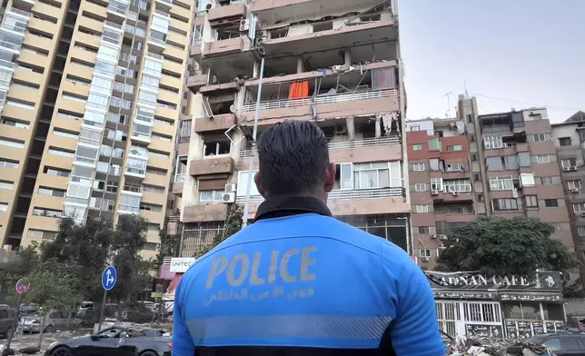 A Lebanese policeman looks at damaged apartments that were hit by Israeli strike early Monday, Sept. 30, 2024, in Beirut, Lebanon. (AP Photo/Hussein Malla)