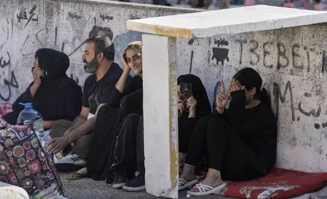 Families sit on the ground in Martyrs' square after fleeing the Israeli airstrikes in Beirut's southern suburbs, Saturday, Sept. 28, 2024. (AP Photo/Bilal Hussein)