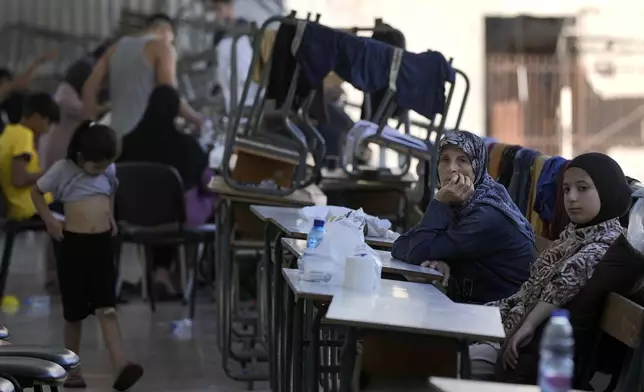 Displaced women and children sit in a classroom in Beirut, after fleeing the Israeli airstrikes in the south, Thursday, Sept. 26, 2024. (AP Photo/Bilal Hussein)