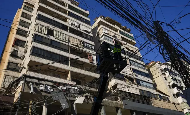 Municipality workers remove power cables in front of damaged buildings at the site of an Israeli airstrike in Beirut's southern suburb, Thursday, Sept. 26, 2024. (AP Photo/Hassan Ammar)