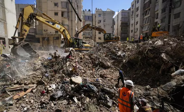 Emergency workers use excavators to clear the rubble at the site of Friday's Israeli strike in Beirut's southern suburbs, Lebanon, Monday, Sept. 23, 2024. (AP Photo/Hassan Ammar)