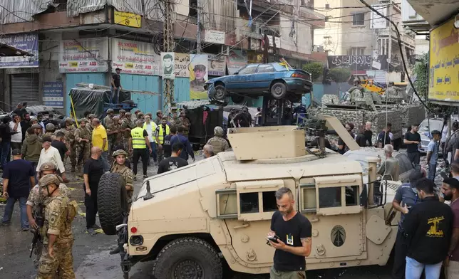 A forklift removes a damaged car as Lebanese army and emergency workers gather at the scene of an Israeli airstrike in Beirut's southern suburbs, Tuesday, Sept. 24, 2024. (AP Photo/Hassan Ammar)