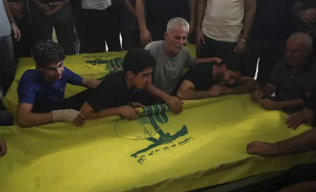 Relatives mourn over the coffins of Hezbollah members who were killed in an Israeli airstrikes, during their funeral procession in the southern village of Saksakieh, Lebanon, Tuesday, Sept. 24, 2024. (AP Photo/Mohammed Zaatari)