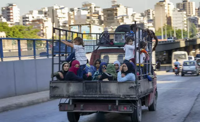 Lebanese citizens who fled from the southern villages amid ongoing Israeli airstrikes Monday, sit in a pickup in Beirut, Tuesday, Sept. 24, 2024. (AP Photo/Hassan Ammar)