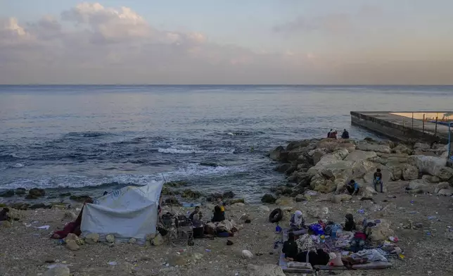 Families sleep on Beirut's corniche after fleeing the Israeli airstrikes in Beirut's southern suburb, Lebanon, Monday, Sept. 30, 2024. (AP Photo/Hassan Ammar)