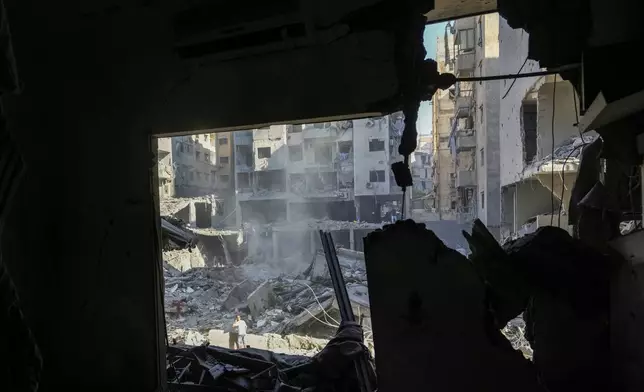 People check the site of an Israeli airstrike in Beirut's southern suburbs, Sunday, Sept. 29, 2024. (AP Photo/Hassan Ammar)