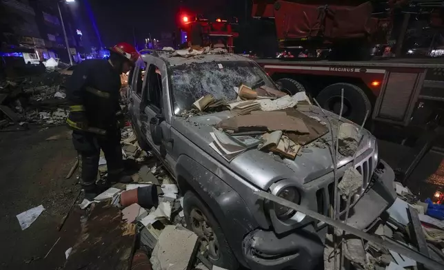 A firefighter inspects a damaged car near a building that was hit in an Israeli airstrike, in Beirut, Lebanon, early Monday, Sept. 30, 2024. (AP Photo/Bilal Hussein)