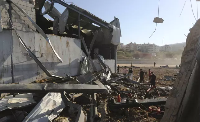 People gather at the site of an Israeli airstrike that hit a hangar in the southern town of Jiyeh, Lebanon, Wednesday, Sept. 25, 2024. (AP Photo/Mohammed Zaatari)