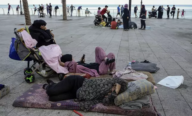 Families sleep on Beirut's corniche after fleeing the Israeli airstrikes in the southern suburbs of Dahiyeh, Sunday, Sept. 29, 2024. (AP Photo/Bilal Hussein)