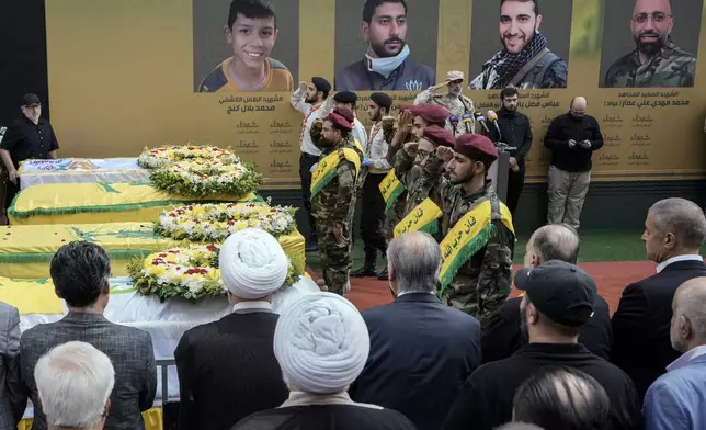 Hezbollah fighters salute as they stand next to the coffins of four victims who were killed Tuesday after their handheld pagers exploded, during their funeral procession in the southern suburb of Beirut, Lebanon, Wednesday, Sept. 18, 2024. (AP Photo/Bilal Hussein)