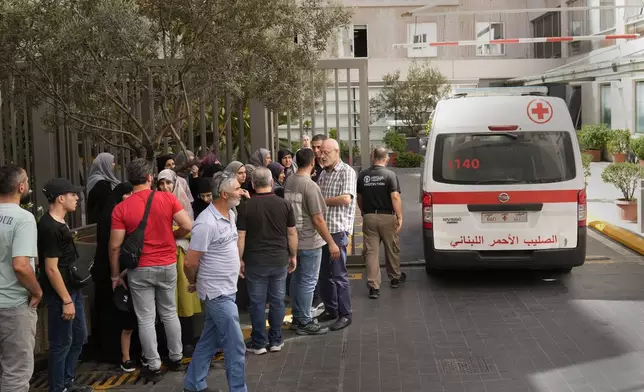 Lebanese Red Cross ambulance passes next of the families of victims who were injured on Monday by their exploding handheld pagers, at the emergency entrance of the American University hospital, in Beirut, Lebanon, Wednesday, Sept. 18, 2024. (AP Photo/Hussein Malla)