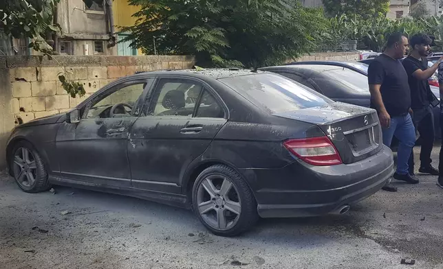 Lebanese security officers stand next of a partly damaged car after what is believed to be the result of a walkie-talkie exploding inside it, in the southern port city of Sidon, Lebanon, Wednesday, Sept. 18, 2024. (AP Photo/Mohammed Zaatari)