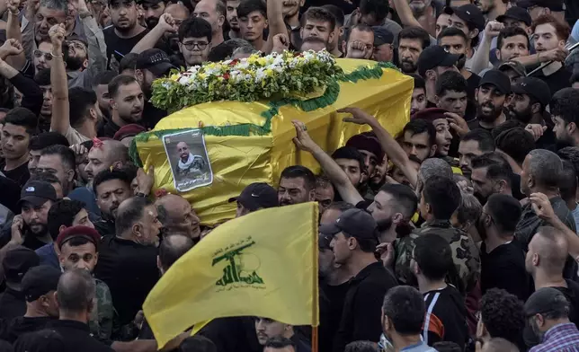 Mourners carry the coffin of Mohammed Mahdi, son of Hezbollah legislator Ali Ammar, who was killed Tuesday after his handheld pager exploded, in the southern suburb of Beirut, Lebanon, Wednesday, Sept. 18, 2024. (AP Photo/Bilal Hussein)