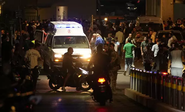 People gather around an ambulance carrying wounded people whose handheld pager exploded, at the emergency entrance of the American University hospital in Beirut, Lebanon, Tuesday, Sept. 17, 2024. (AP Photo/Hassan Ammar)